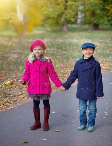 Niños caminando en el hermoso parque de otoño en el cálido día soleado de otoño . — Foto de Stock