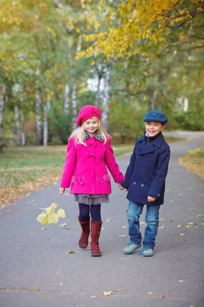 Kinder spazieren an einem warmen, sonnigen Herbsttag im wunderschönen Herbstpark. — Stockfoto