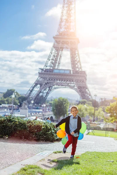 Menino com um monte de balões coloridos em Paris perto da Torre Eiffel . — Fotografia de Stock