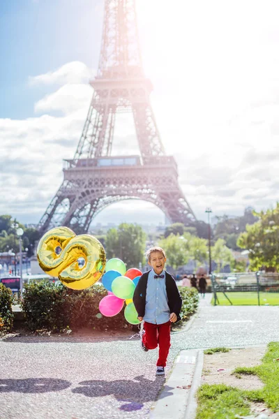 Boy with bunch of colorful balloons in Paris near the Eiffel tower. — Stock Photo, Image