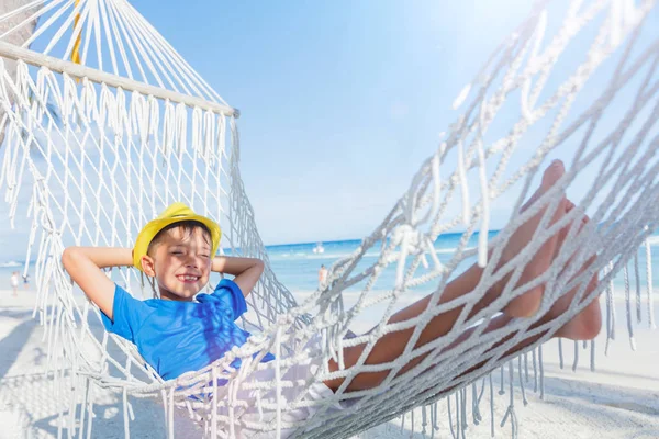 Menino relaxante em uma praia tropical em rede . — Fotografia de Stock