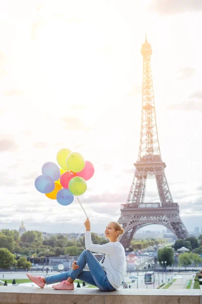 パリのエッフェル塔の近くの色とりどりの風船の束を持つ少女. — ストック写真