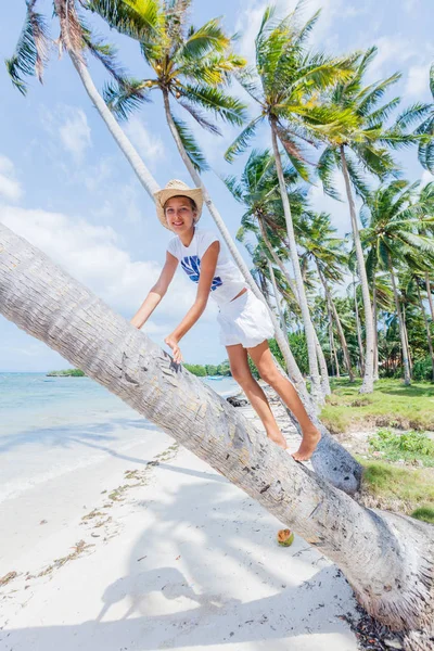 Mutlu kız bir palmiye ağacı bir tropikal Beach oturur