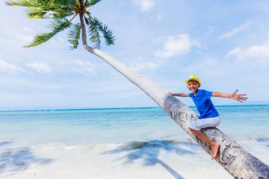 genç çocuk bir palmiye ağacı bir tropikal Beach oturur