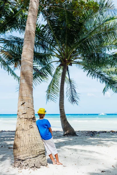 Genç çocuk avuç içi ağaç ile tropikal bir plajda eğlenmek — Stok fotoğraf