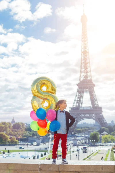 パリのエッフェル塔の近くの色とりどりの風船の束を持つ少年. — ストック写真