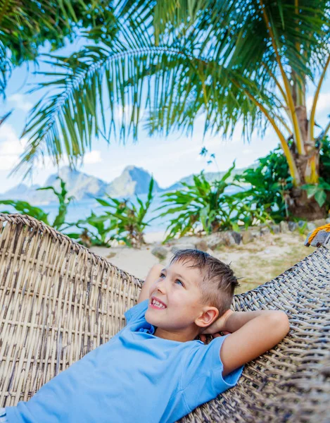 Маленький хлопчик відпочиває на тропічному пляжі в гамаку . — стокове фото