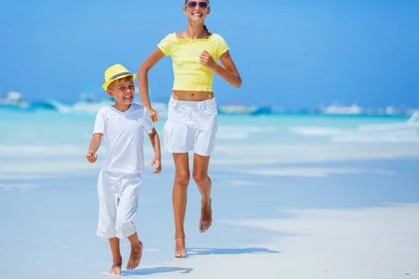 Un chico con su hermana divirtiéndose en la playa tropical del océano. Niño durante las vacaciones familiares en el mar . — Foto de Stock