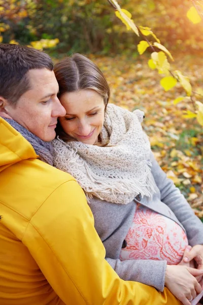 Gravid kvinna och man som är avkopplande på hösten park — Stockfoto