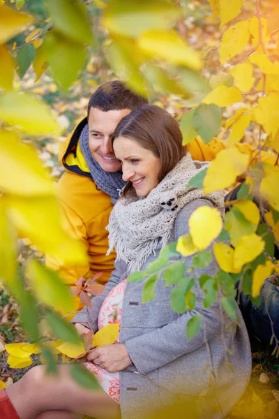 怀孕的女人和男人放松在秋天的公园 — 图库照片