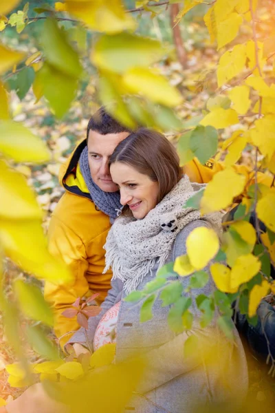 Donna incinta e uomo rilassante al parco autunnale — Foto Stock