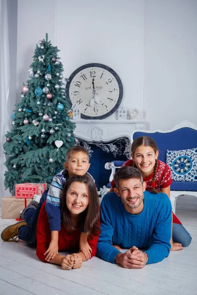 Föräldrar och två söta barn ha roligt nära julgran inomhus. — Stockfoto