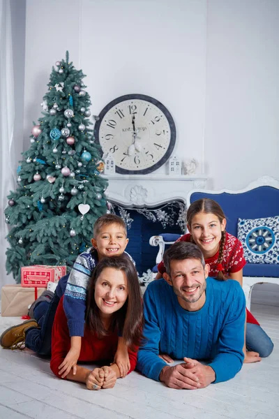 Los padres y dos niños lindos se divierten cerca del árbol de Navidad en el interior . — Foto de Stock