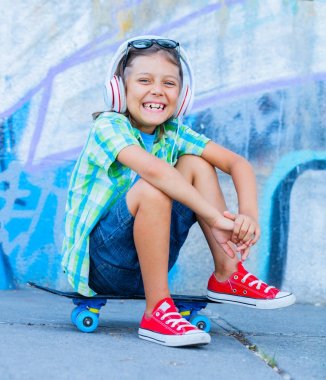 Sevimli çocuk sokakta farklı renkli grafiti duvarlara ile ayakta açık havada, kaykay ile