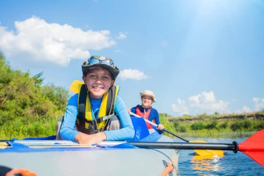 Mutlu çocuk yaz tatilinde güneşli bir günde nehirde kano yapıyor.