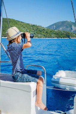 Little boy on board of sailing yacht on summer cruise. Travel adventure, yachting with child on family vacation. clipart