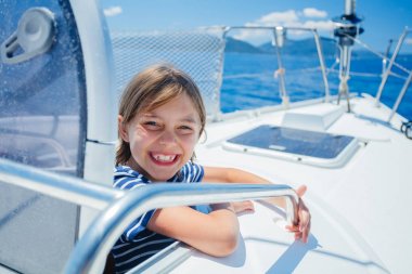 Little boy on board of sailing yacht on summer cruise. Travel adventure, yachting with child on family vacation. clipart