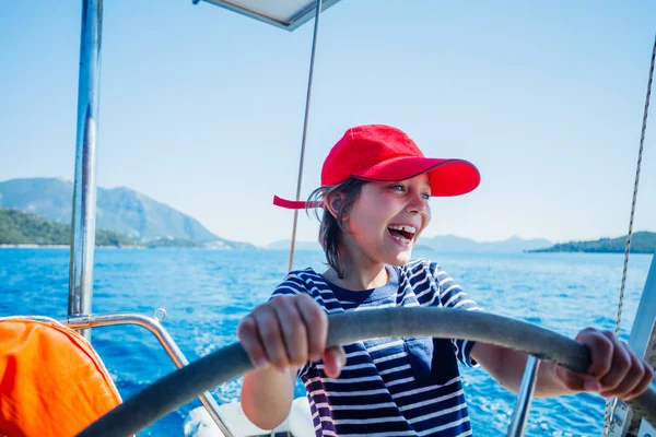 Pequeño capitán a bordo de yate de vela en crucero de verano. Aventura de viaje, yates con niños en vacaciones en familia . — Foto de Stock