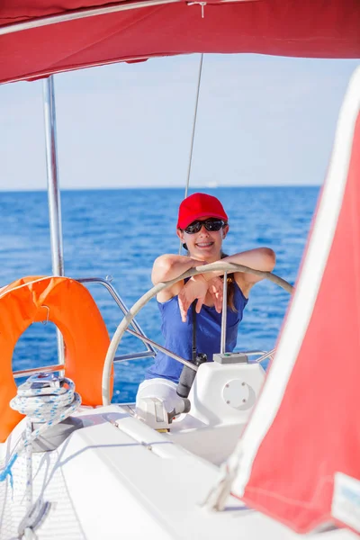 Girl captain on board of sailing yacht on summer cruise. Travel adventure, yachting with child on family vacation. Stock Photo