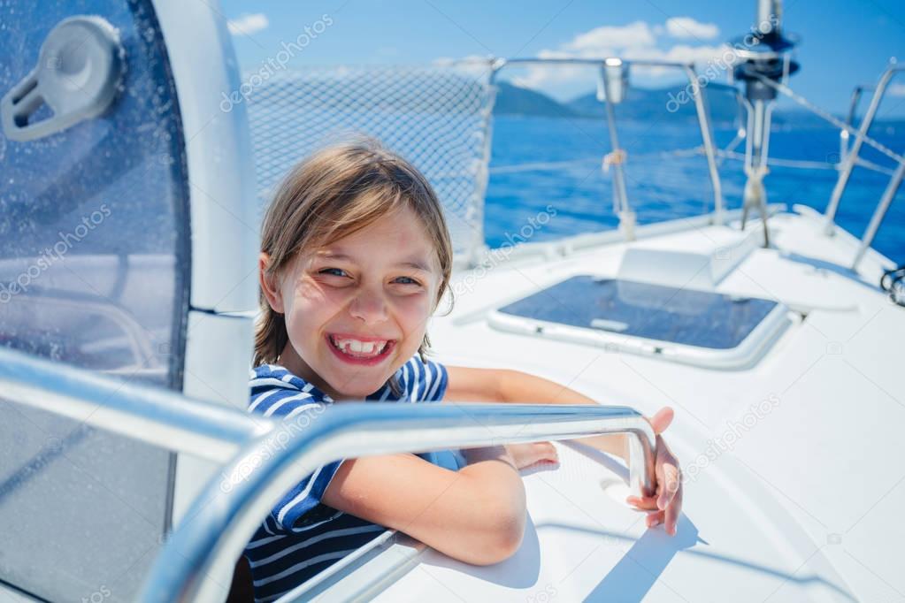 Little boy on board of sailing yacht on summer cruise. Travel adventure, yachting with child on family vacation.