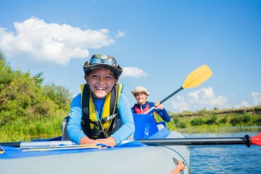 Mutlu çocuk yaz tatilinde güneşli bir günde nehirde kano yapıyor.