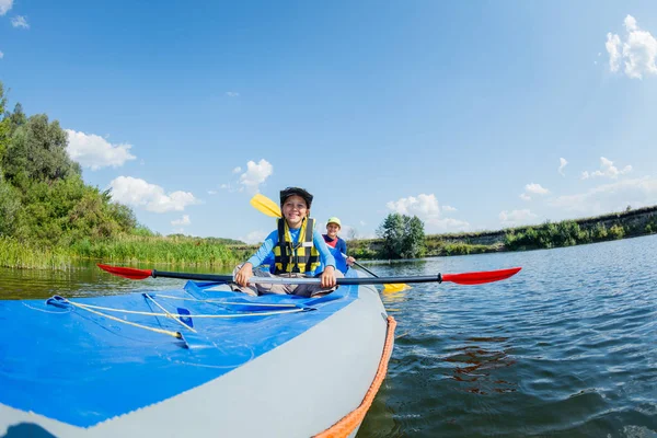 Szczęśliwy chłopiec kajakarstwo na rzece w słoneczny dzień podczas letnich wakacji — Zdjęcie stockowe