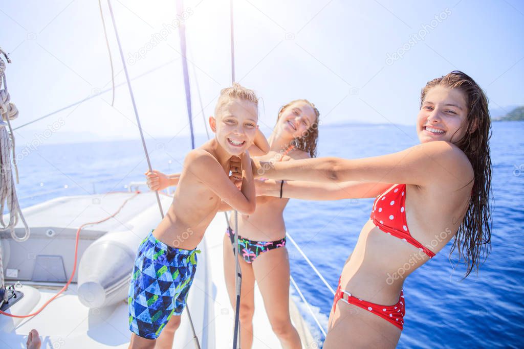 Boy with his sisters on board of sailing yacht on summer cruise.