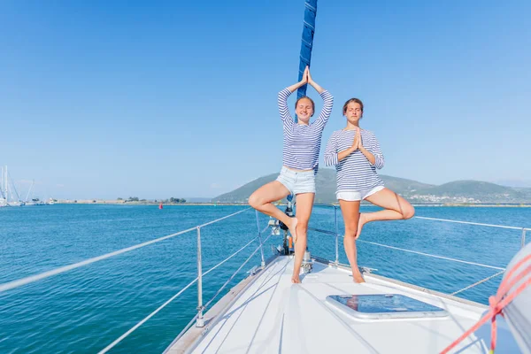 Две девушки практикуют йогу на палубе яхты — стоковое фото