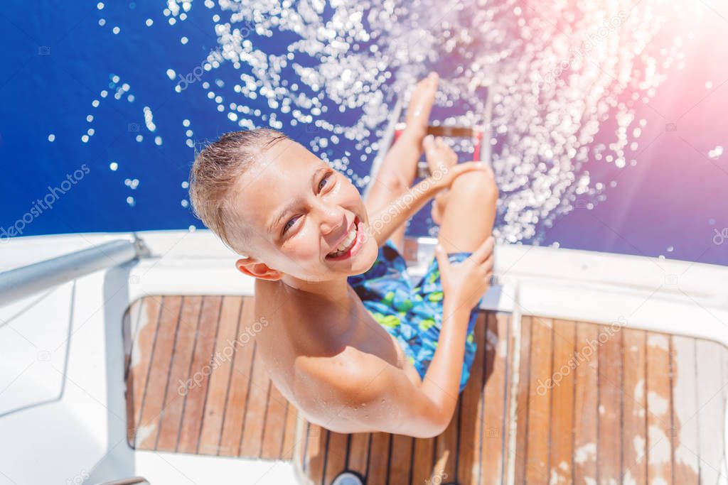 Little boy on board of sailing yacht on summer cruise. Travel adventure, yachting with child on family vacation.