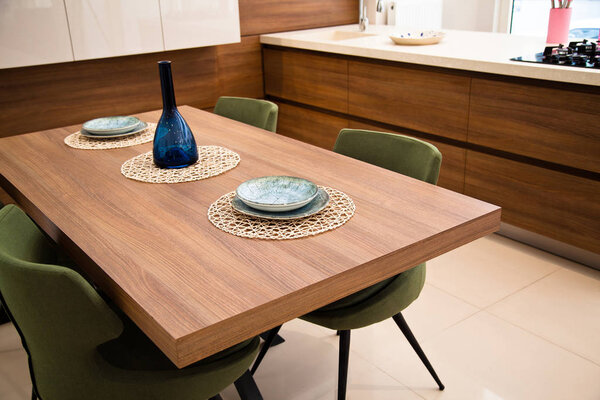 Modern kitchen, wooden walnut dining table and green chairs