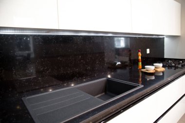 Modern mutfak, beyaz dolaplar ve akrilik lavabo.