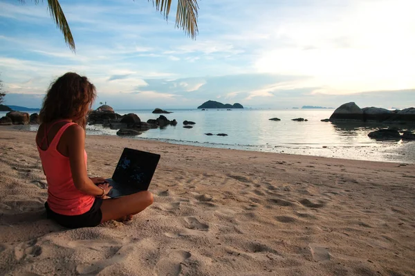 Lady pigiste avec un ordinateur portable sur la plage au coucher du soleil — Photo