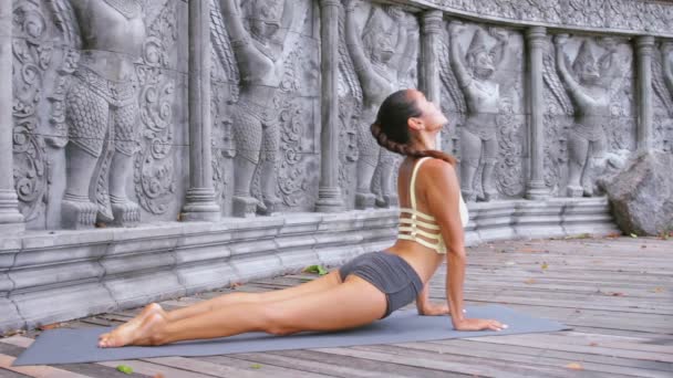 Aziatische jonge vrouw doet hathayoga in verlaten tempel — Stockvideo