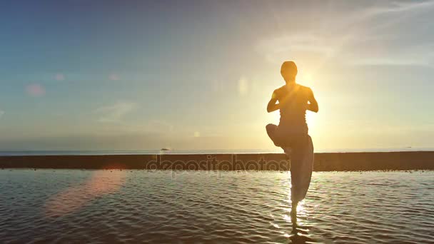 Žena dělá jógu na pláži při západu slunce — Stock video