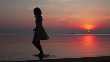 mutlu genç kadın kumsalda ağır çekimde Sunset'teki döne döne