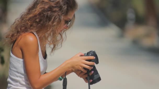 Žena sedí na silnici a dívat se skrz fotografie ve fotoaparátu — Stock video