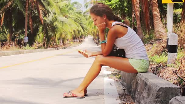 Mujer sentada en el borde de la carretera y mensajes de texto — Vídeos de Stock