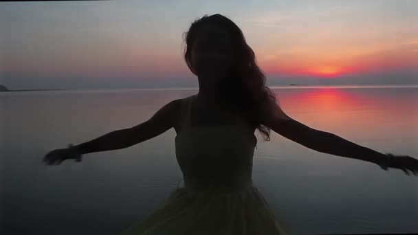 Glückliche junge Frau wirbelt am Strand bei Sonnenuntergang in Zeitlupe — Stockvideo