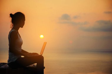 Bayan freelancer günbatımı laptop ile