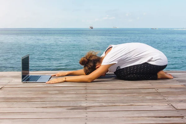 Девушка практикует йогу с ноутбуком — стоковое фото