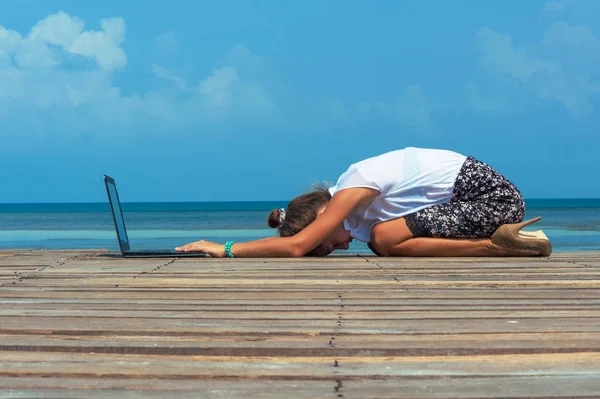 Woman in office suit doing yoga with laptop