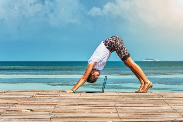 Woman in office suit doing yoga with laptop