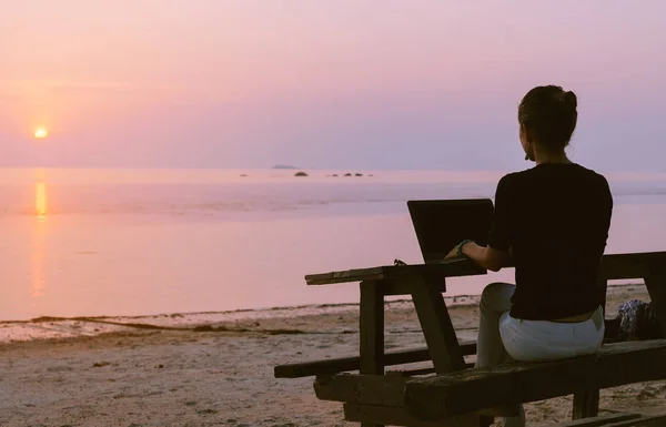 Jovem mulher sentada à mesa com um laptop — Fotografia de Stock