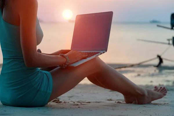 Dame avec un ordinateur portable sur la plage au coucher du soleil — Photo