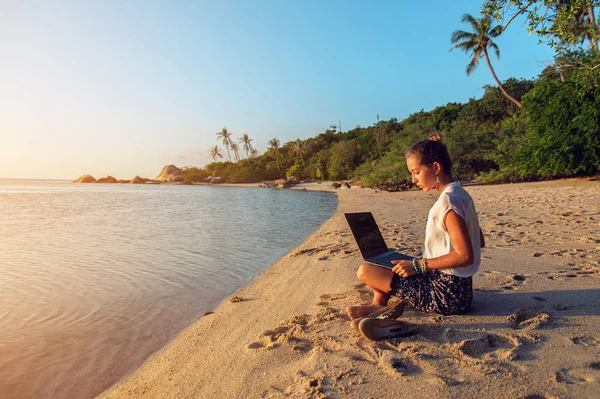 Bir dizüstü bilgisayarda sahilde günbatımı bayanla — Stok fotoğraf