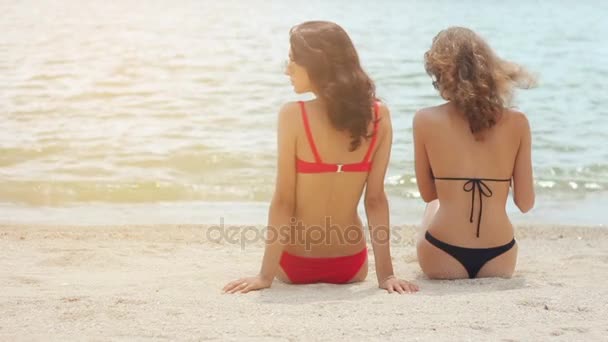 Vista posteriore di donne sexy in costume da bagno seduto sulla spiaggia di sabbia — Video Stock