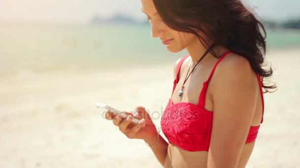 Jovem atraente usando seu telefone na praia — Vídeo de Stock