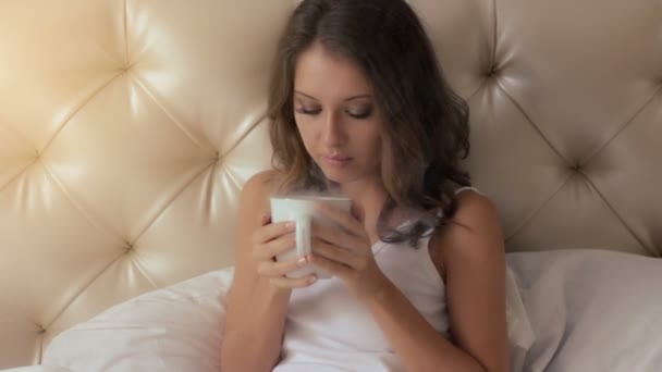 Joven mujer sonriendo y sosteniendo una taza de café caliente — Vídeos de Stock