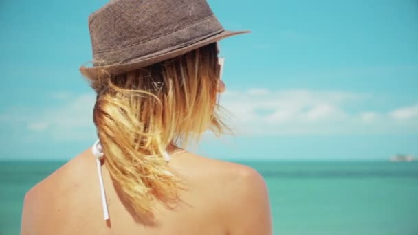 Donna con grande cappello da sole guardando indietro alla fotocamera sorridente rallentatore — Video Stock