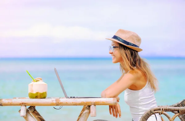 若い女性がビーチでノート パソコンを使用しています。フリーランスの仕事 — ストック写真